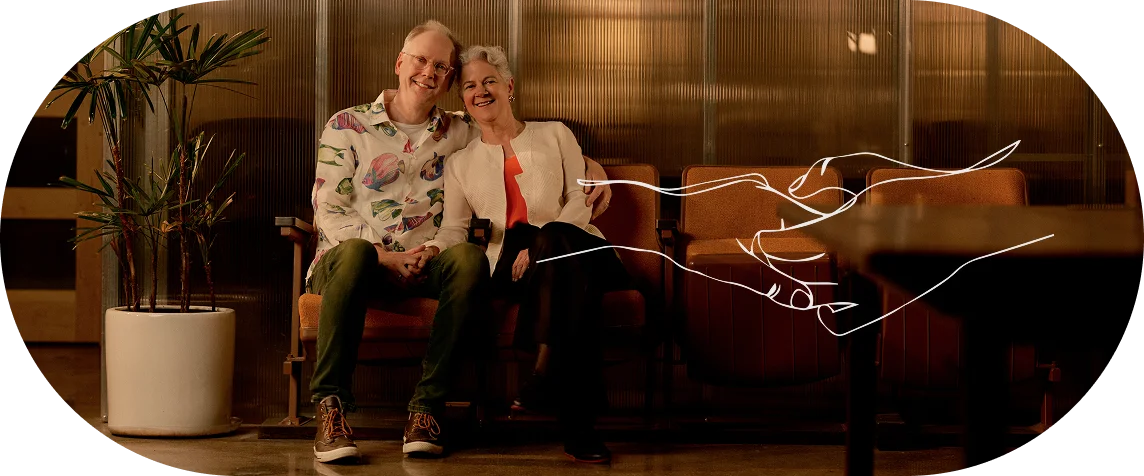 Elderly couple relaxing on couch at home in warm, cozy living room with ambient lighting - In Los Angeles, CA