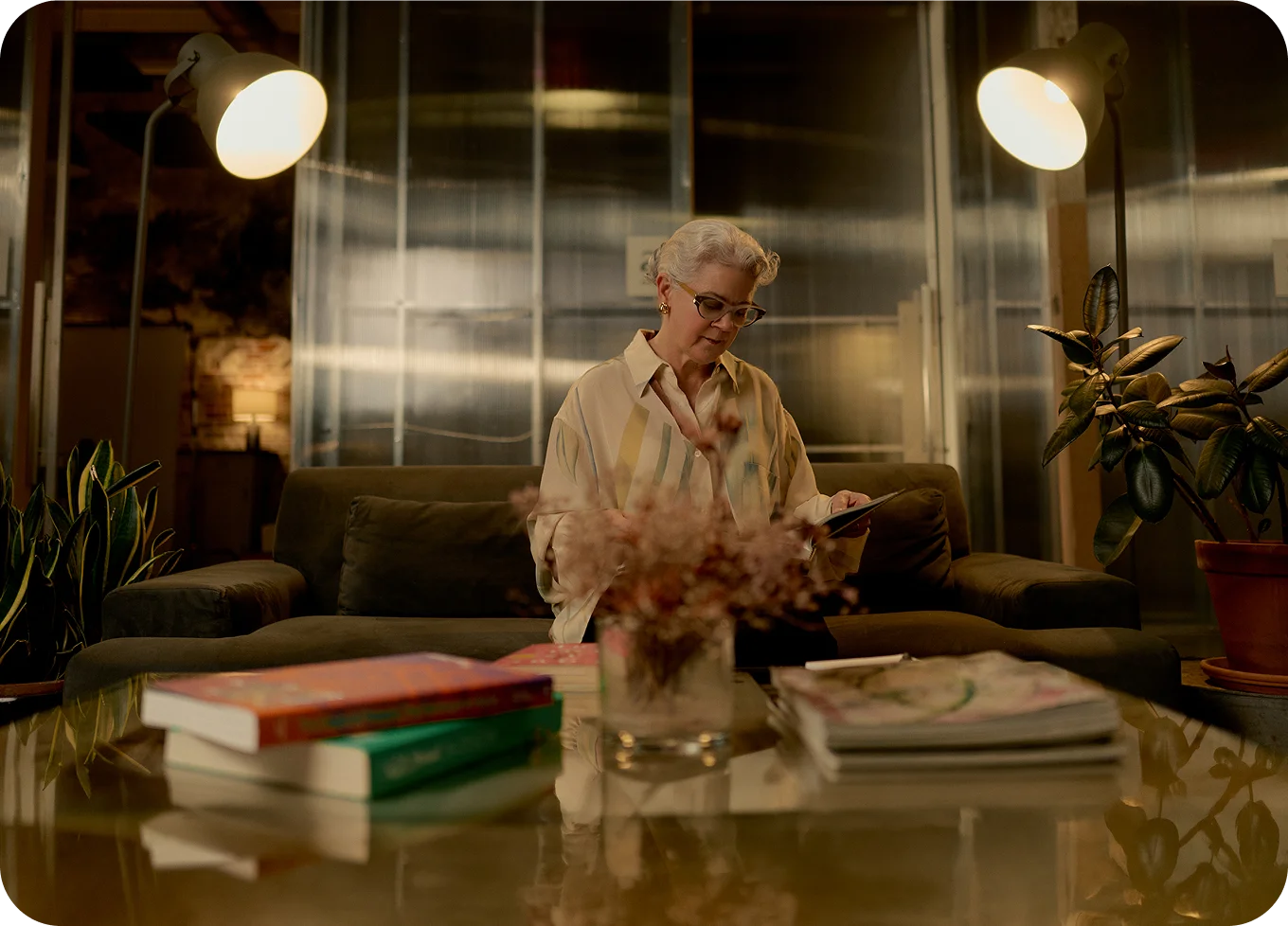 Alex Szablya MA, LMHC in white ruffled blouse working at illuminated desk in modern office with plants and warm lighting - Counselor in Los Angeles, CA