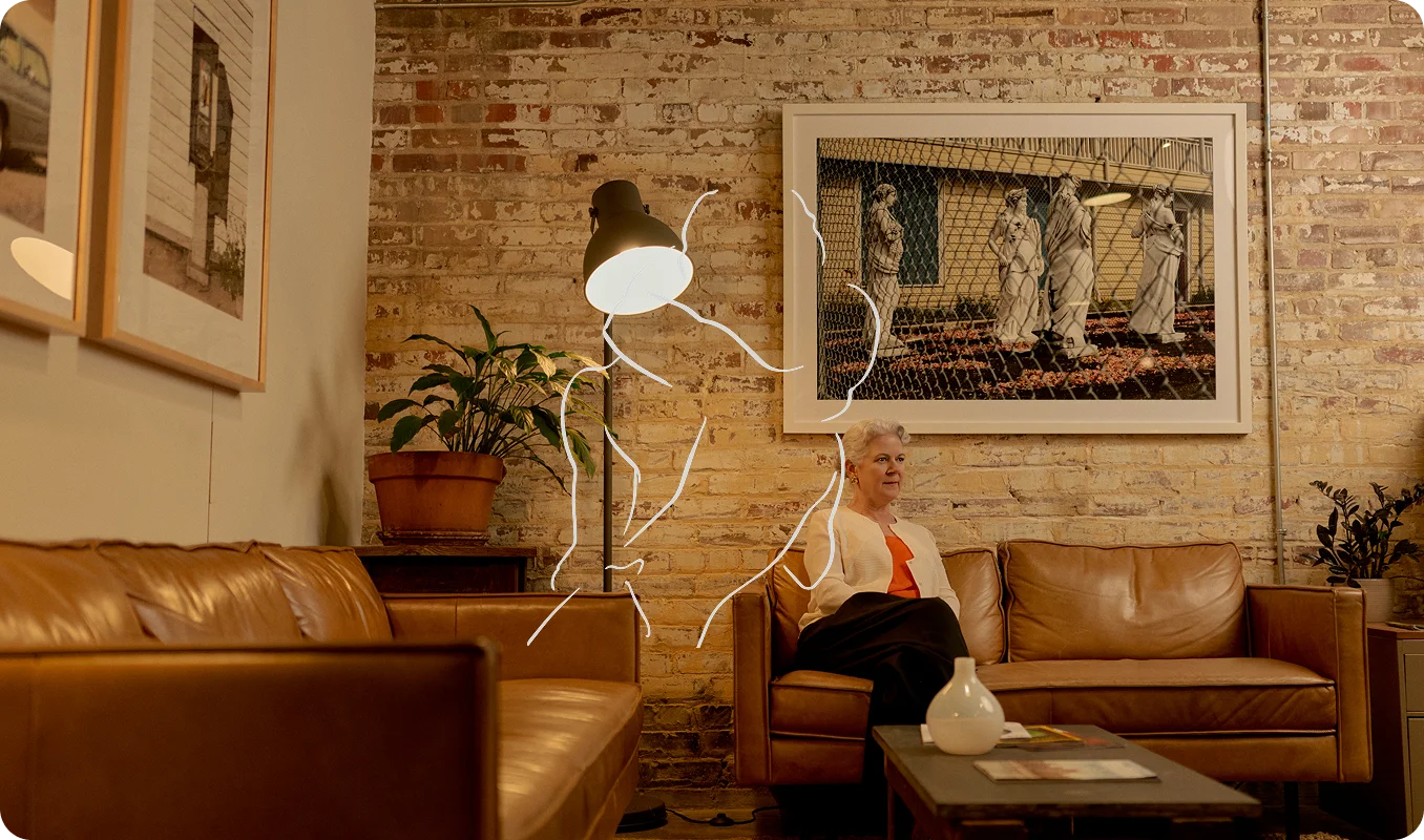 Alex Szablya MA, LMHC relaxing on tan leather sofa in modern living room with exposed brick wall and ambient lighting - In Los Angeles, CA