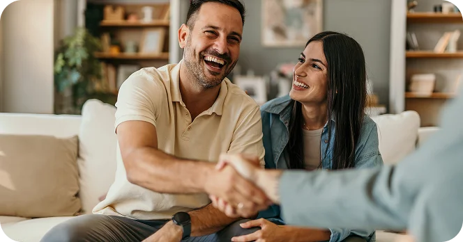 Happy couple shaking hands with advisor or real estate agent during home consultation meeting - In Los Angeles, CA